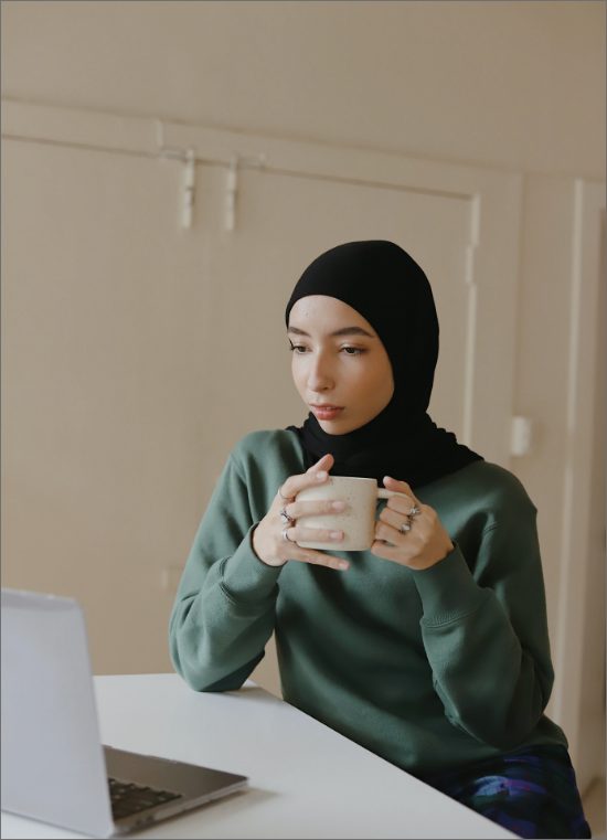 a woman holding a cup of tea and on a video call